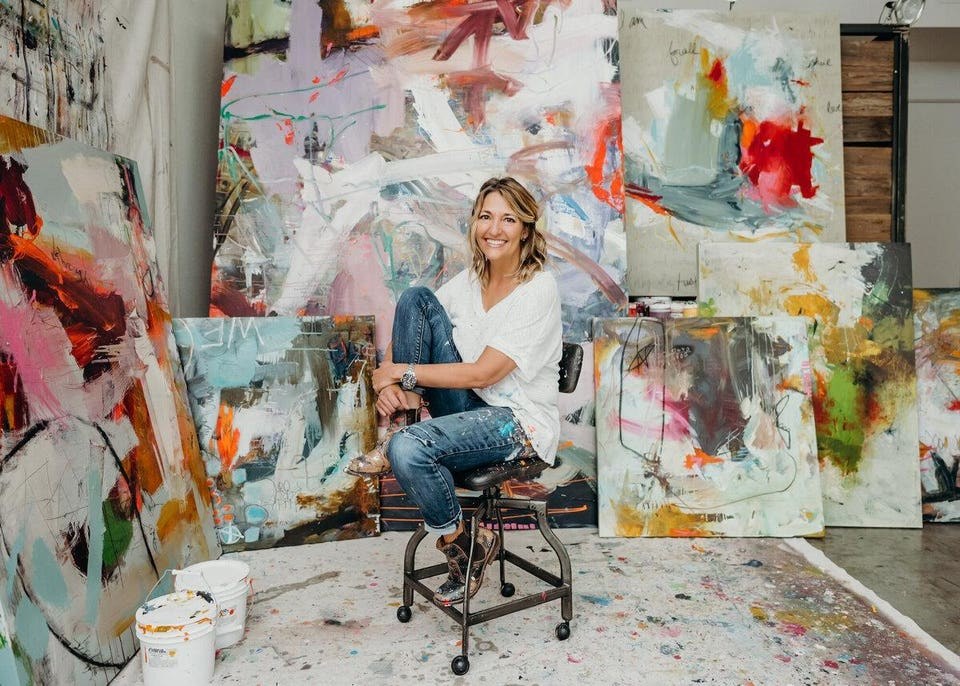 Jodie King sits on a stool amongst her art